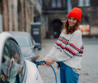 Mujer cargando vehículo eléctrico.