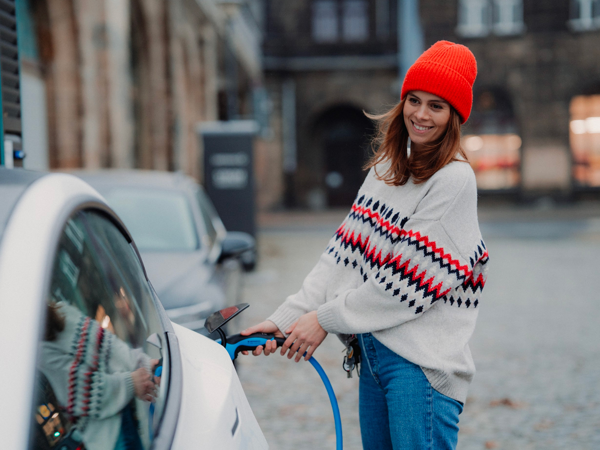 Mujer cargando vehículo eléctrico.