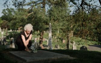 Mujer dejando flores a un ser querido en el cementerio_Cuánto cuesta morirse en España en 2024