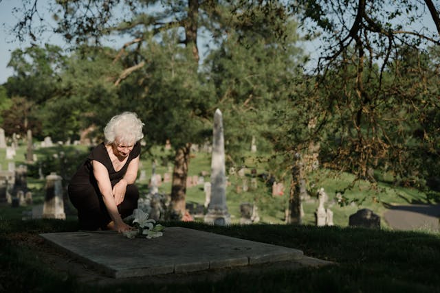 Mujer dejando flores a un ser querido en el cementerio_Cuánto cuesta morirse en España en 2024