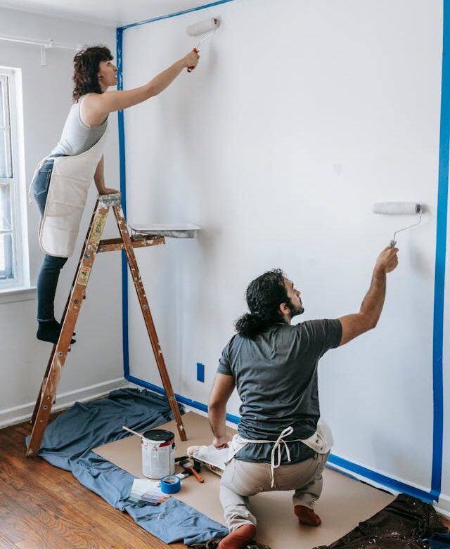 Dos personas pintando su piso. Finanzas de un piso compartido.