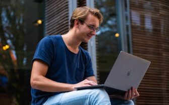 Estudiante sentado con un portátil. Formas de pagar tus estudios universitarios.