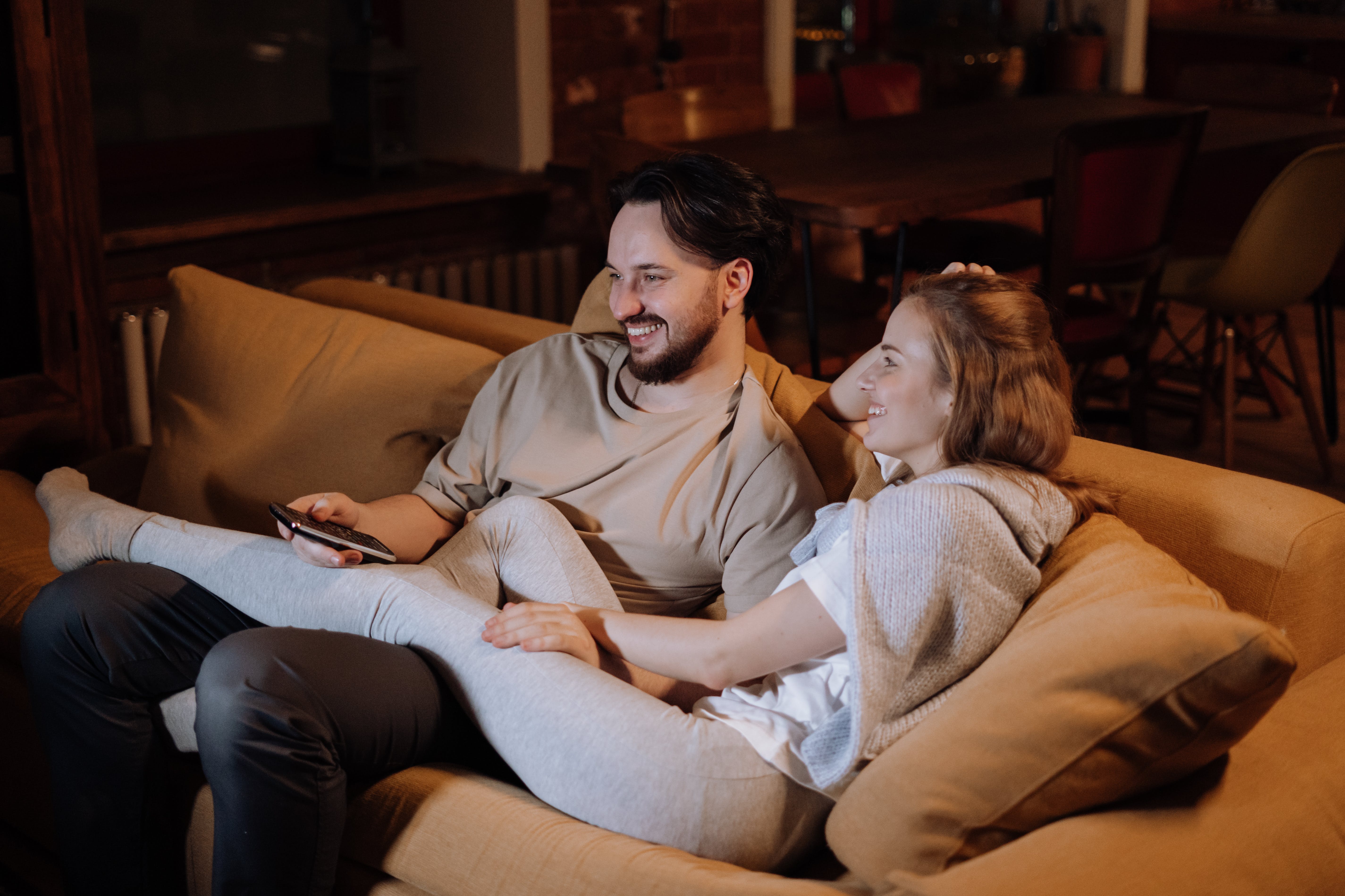 Pareja feliz en el sofá después de instalar domótica en su casa