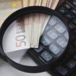 Una lupa encima de unos billetes y una calculadora.