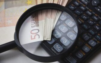 Una lupa encima de unos billetes y una calculadora.