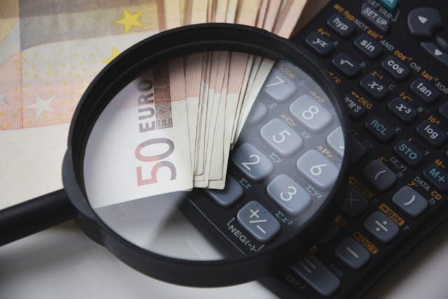 Una lupa encima de unos billetes y una calculadora.