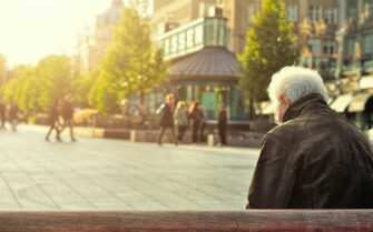 Un adulto mayor sentando en un banco.