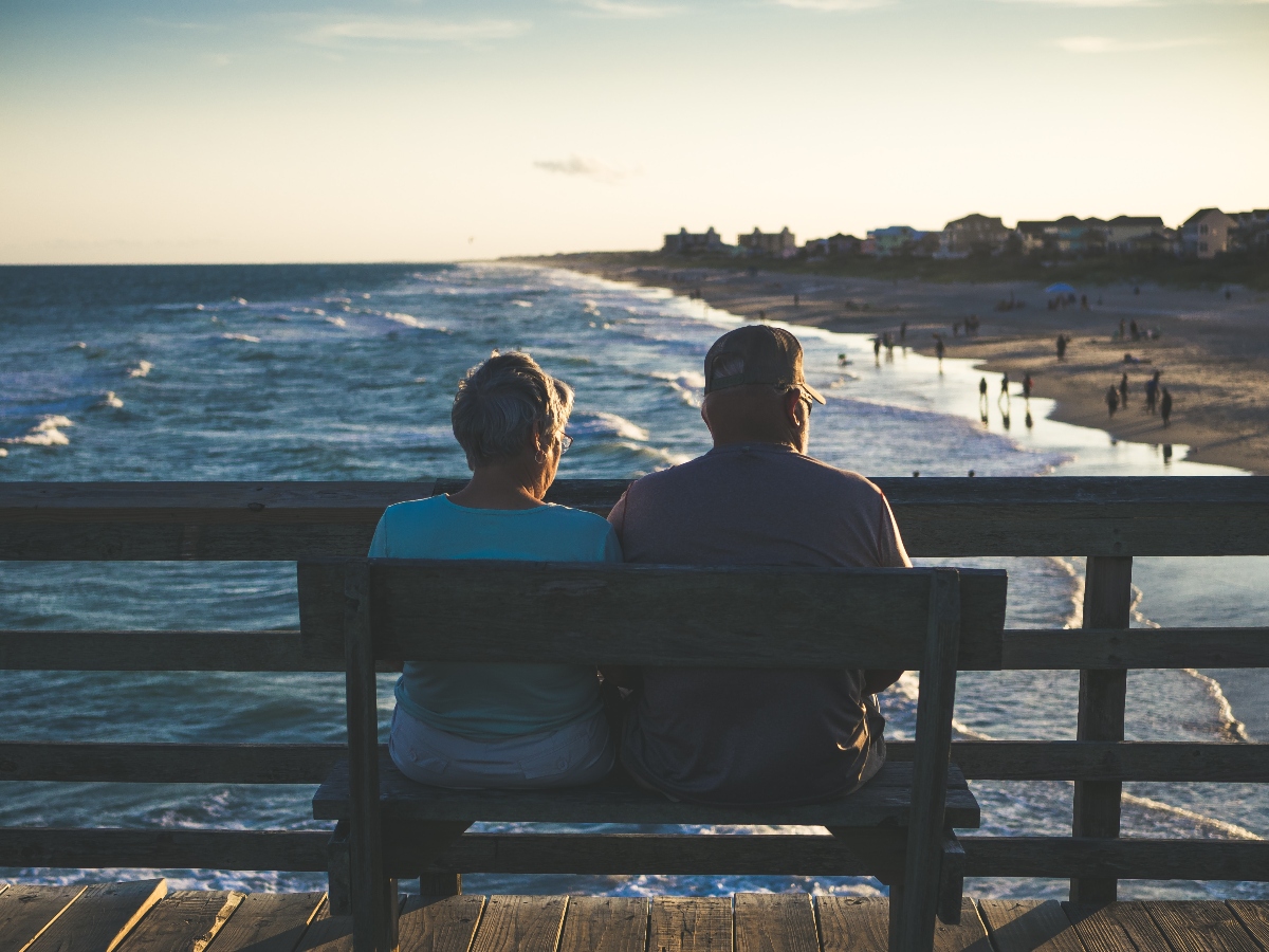 Una pareja de jubilados en un banco frente al océano.