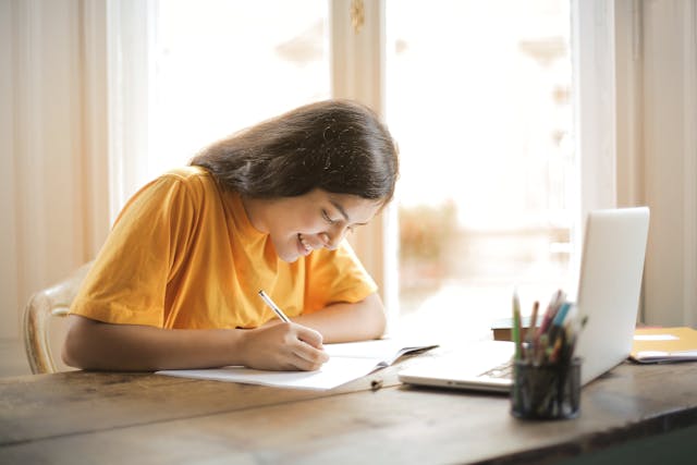 Chica apuntando en su libreta las principales ayudas y becas públicas para estudiantes