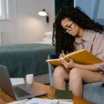 Mujer en su casa escribiendo en una libreta.