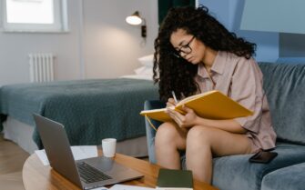 Mujer en su casa escribiendo en una libreta.