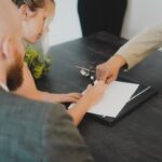 Una mujer con su abogado firmando un documento.
