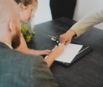 Una mujer con su abogado firmando un documento.