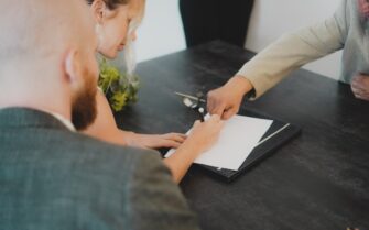 Una mujer con su abogado firmando un documento.