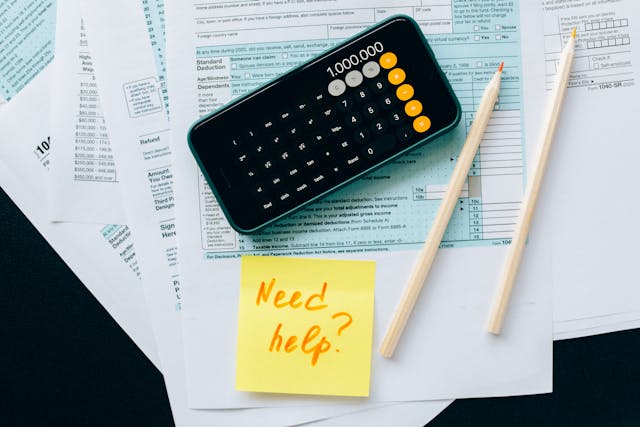 Fichas com números, calculadora del móvil abierta y un post-it con la frase "Need help?"
