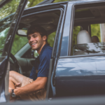 Hombre en el coche con la puerta abierta.