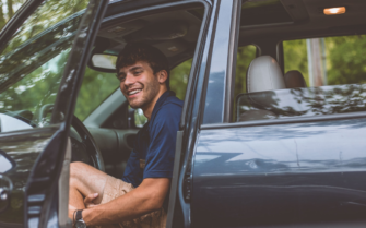Hombre en el coche con la puerta abierta.