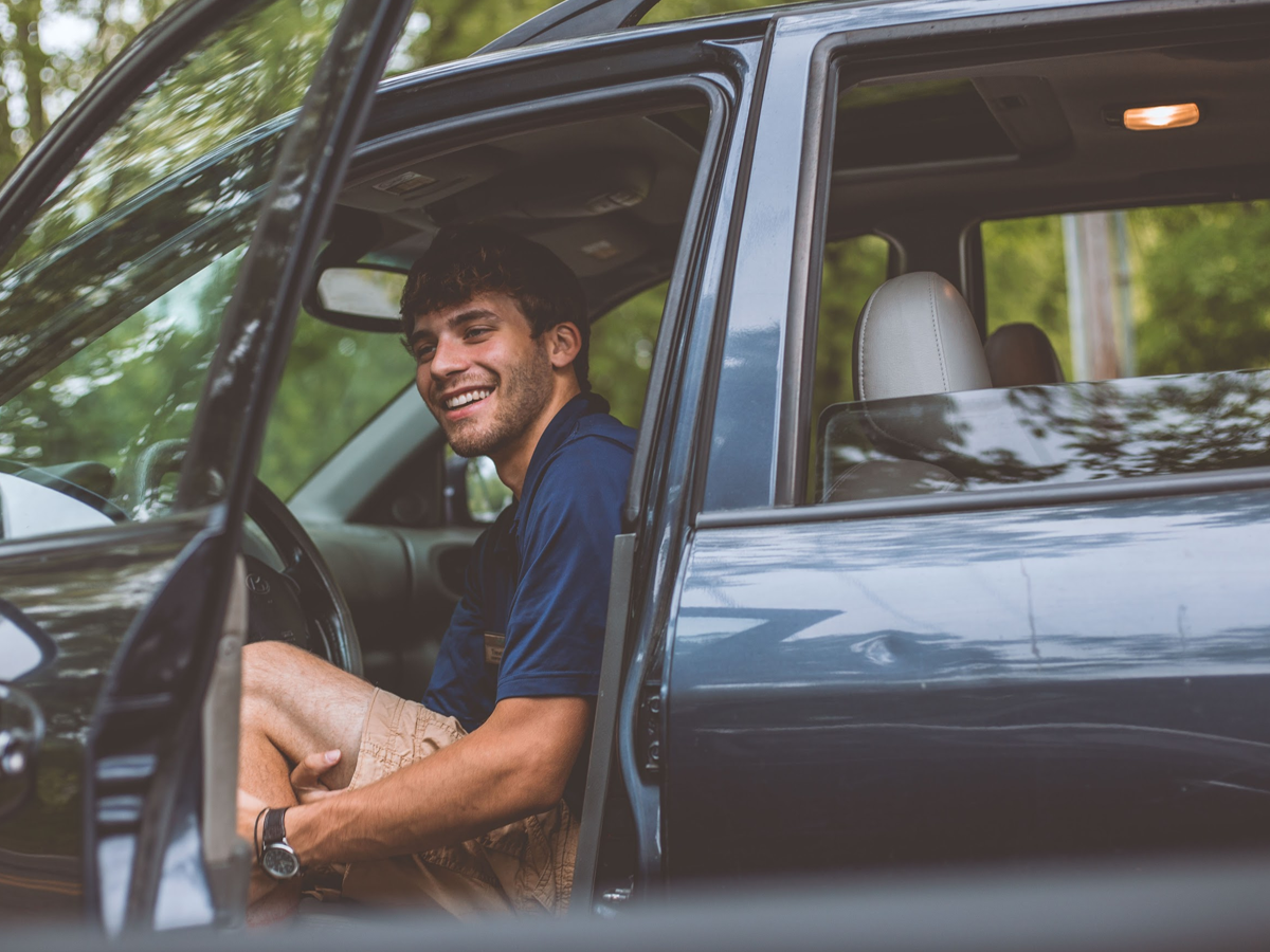 Hombre en el coche con la puerta abierta.