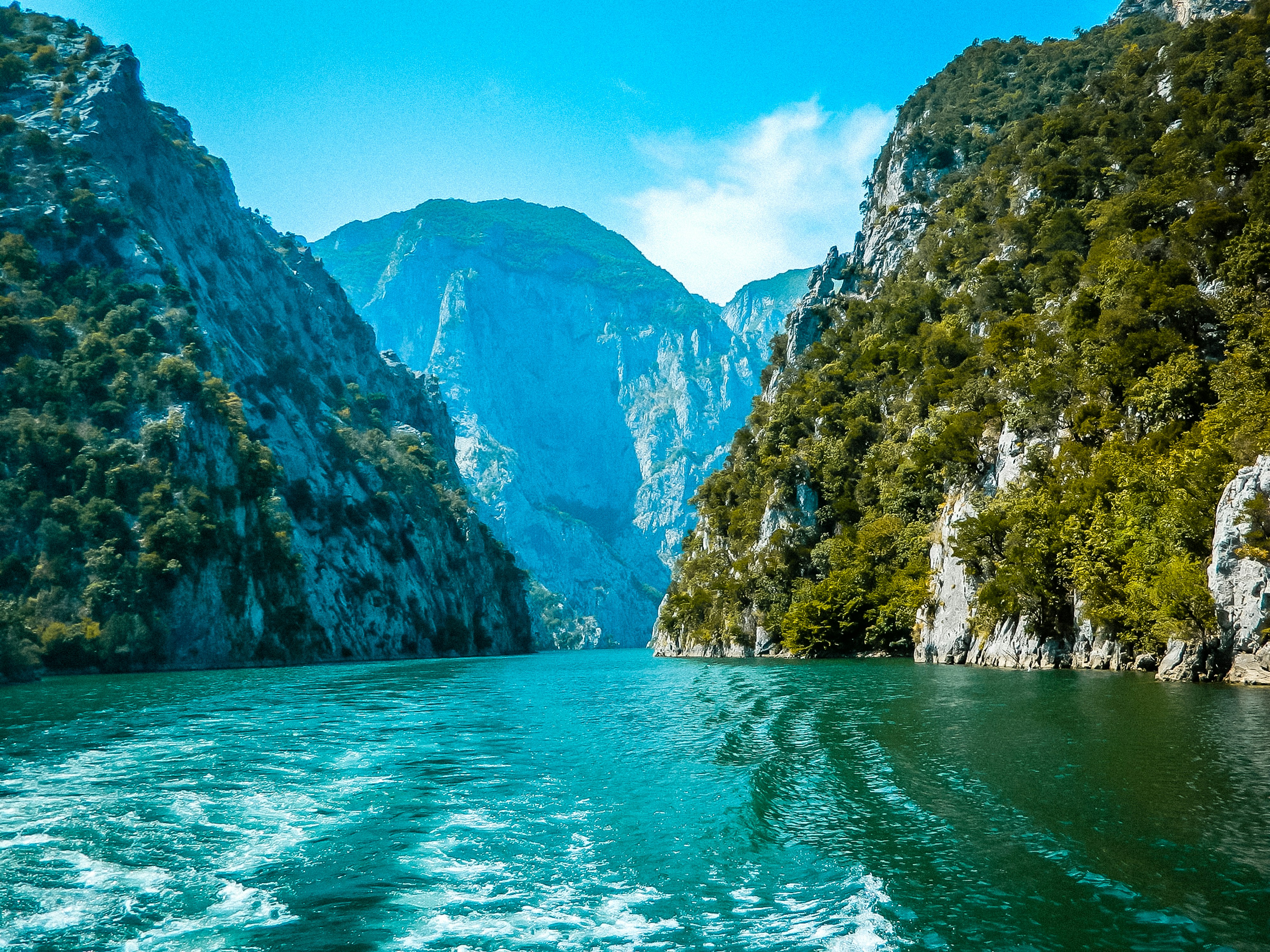 Vista a ras de agua de uno de los lagos más bonitos de Albania El lago Komani rodeado de verdes montañas