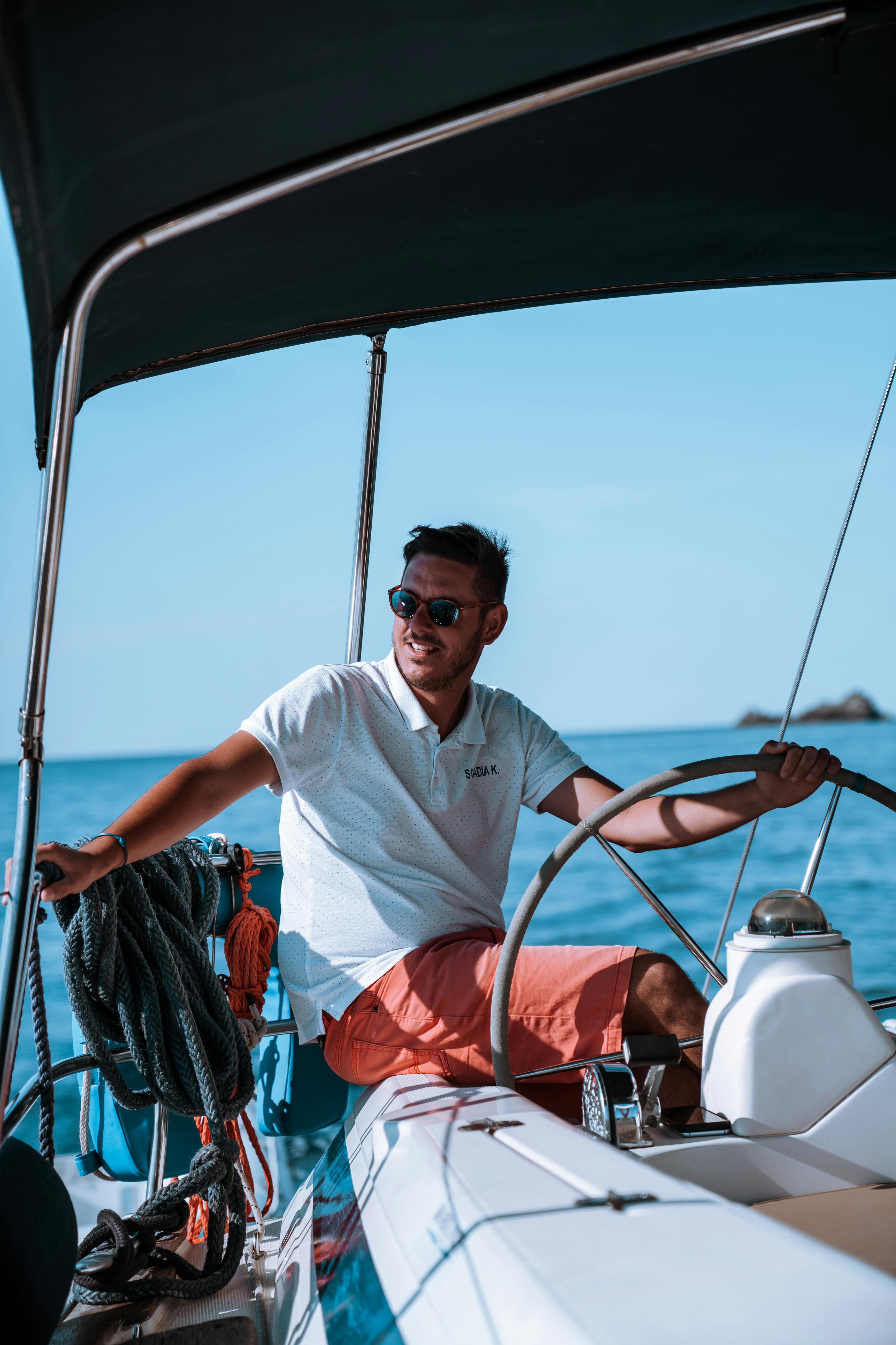 Consejos para reducir el coste de los títulos de patrón de barco Patrón al timón de un barco de recreo, representando el ahorro al obtener el título de navegación mediante el estudio autodidacta o cursos online.