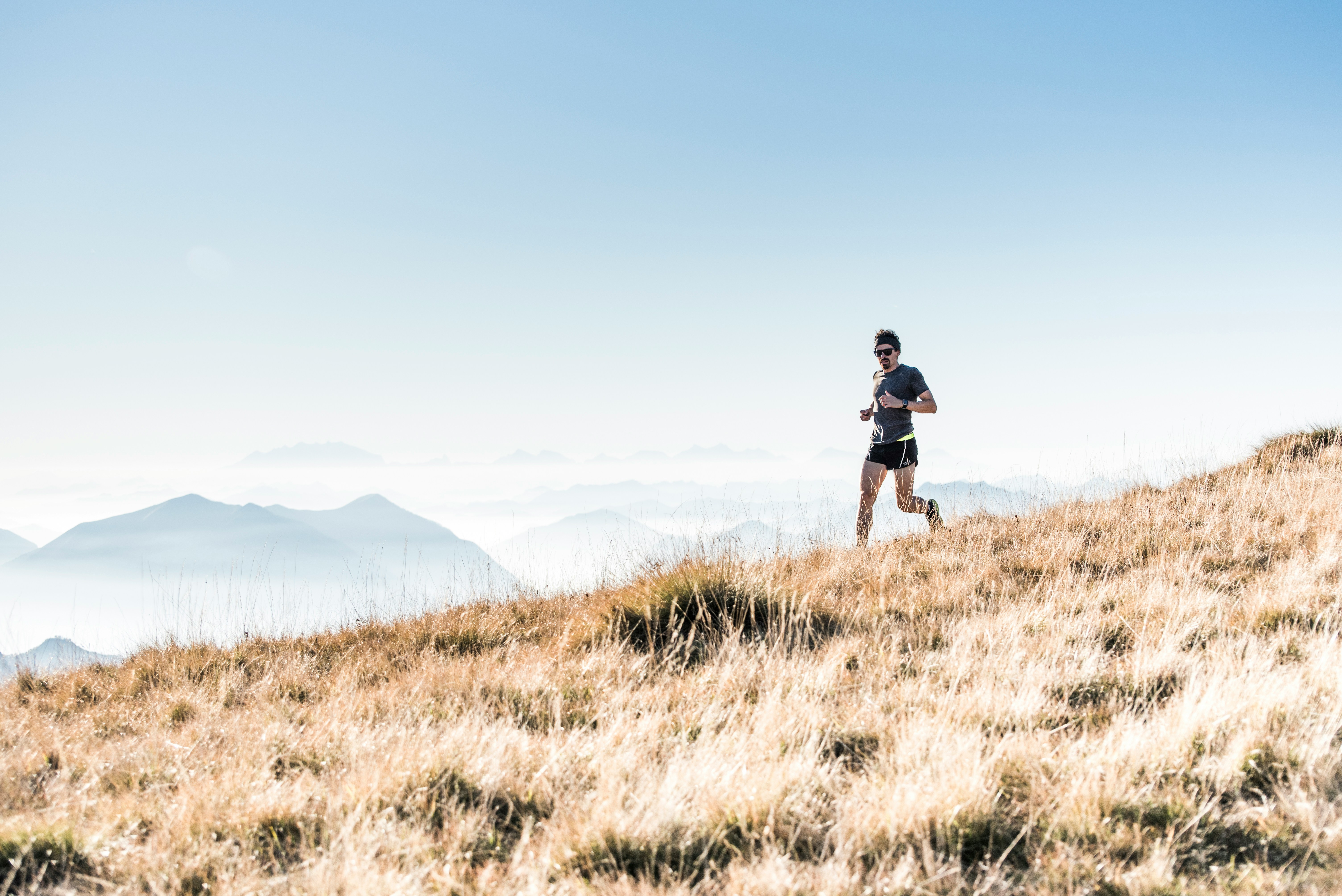 Además de ahorrar, el deporte al aire libre permite conocer lugares increíbles Hombre haciendo trail running con montañas de fondo