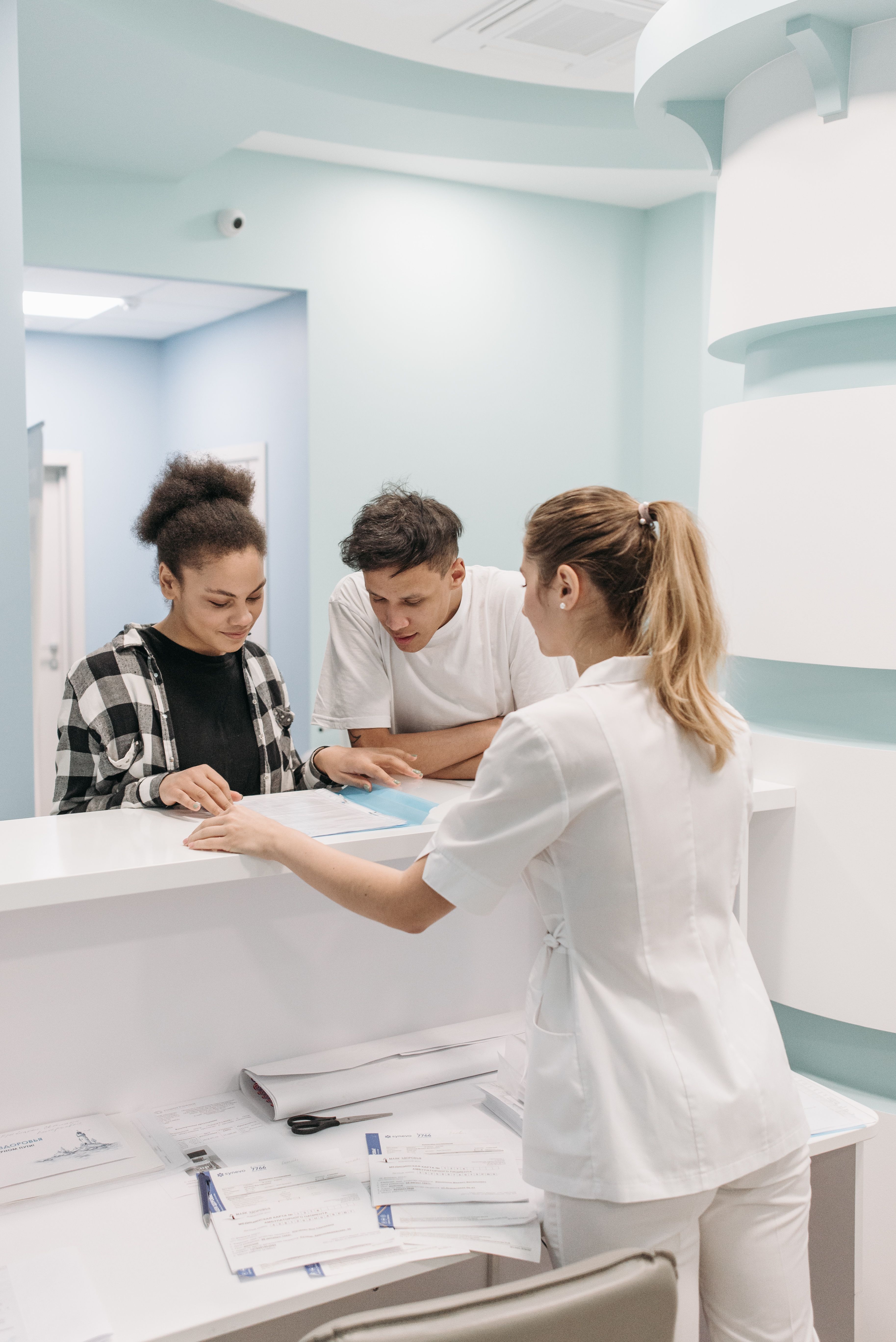 Tarjeta Sanitaria Europea en centros médicos Dos pacientes consultando documentos en la recepción de un centro médico público, representando la cobertura de urgencias y copagos con la Tarjeta Sanitaria Europea.