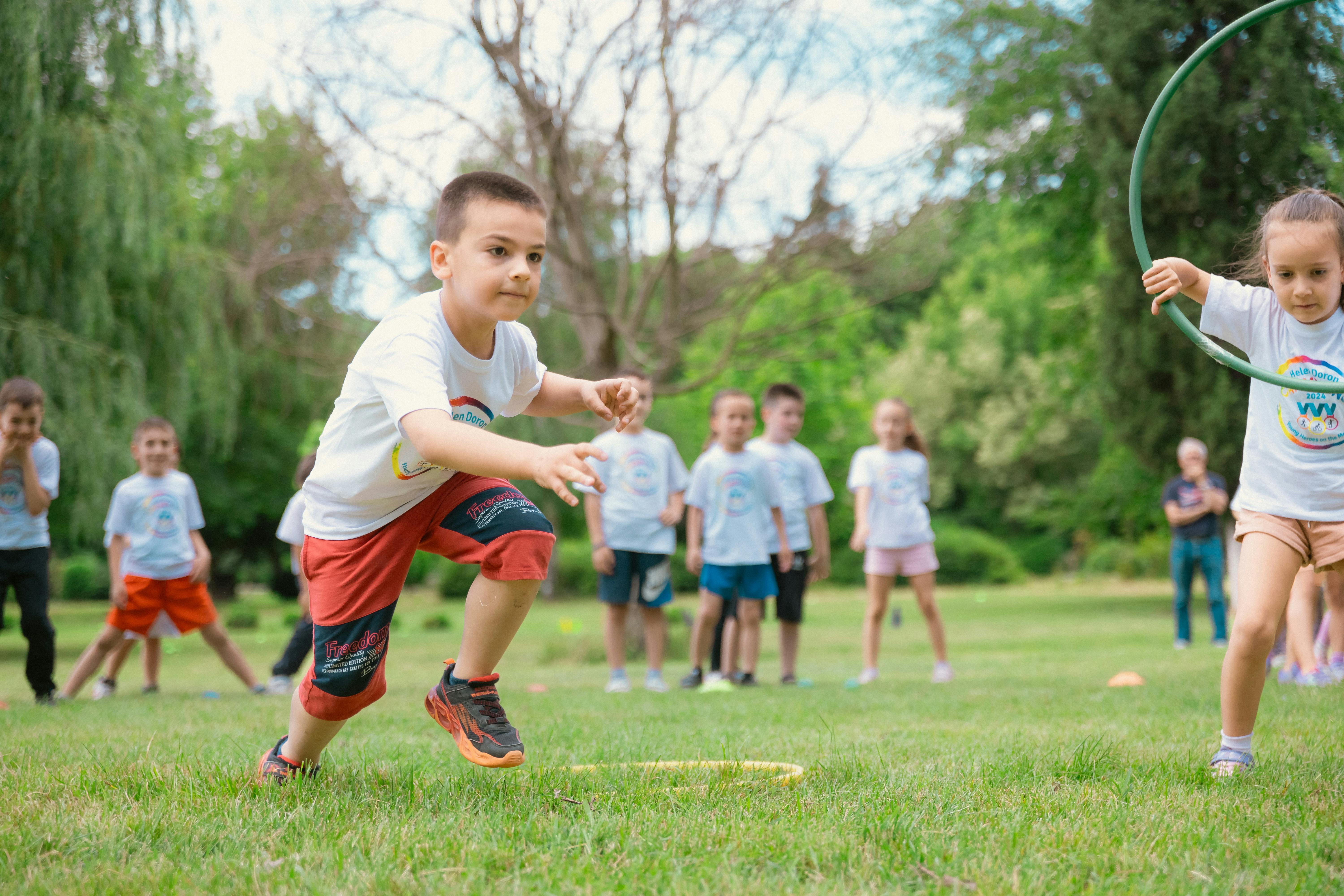 Beneficios pedagógicos y desconexión digital al aire libre. Niños participando en una gymkhana en el césped, ilustrando el desarrollo de la autonomía y las habilidades sociales en los campamentos de verano.