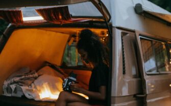 Una chica, mirando fotos, sentada en una furgoneta camperizada,