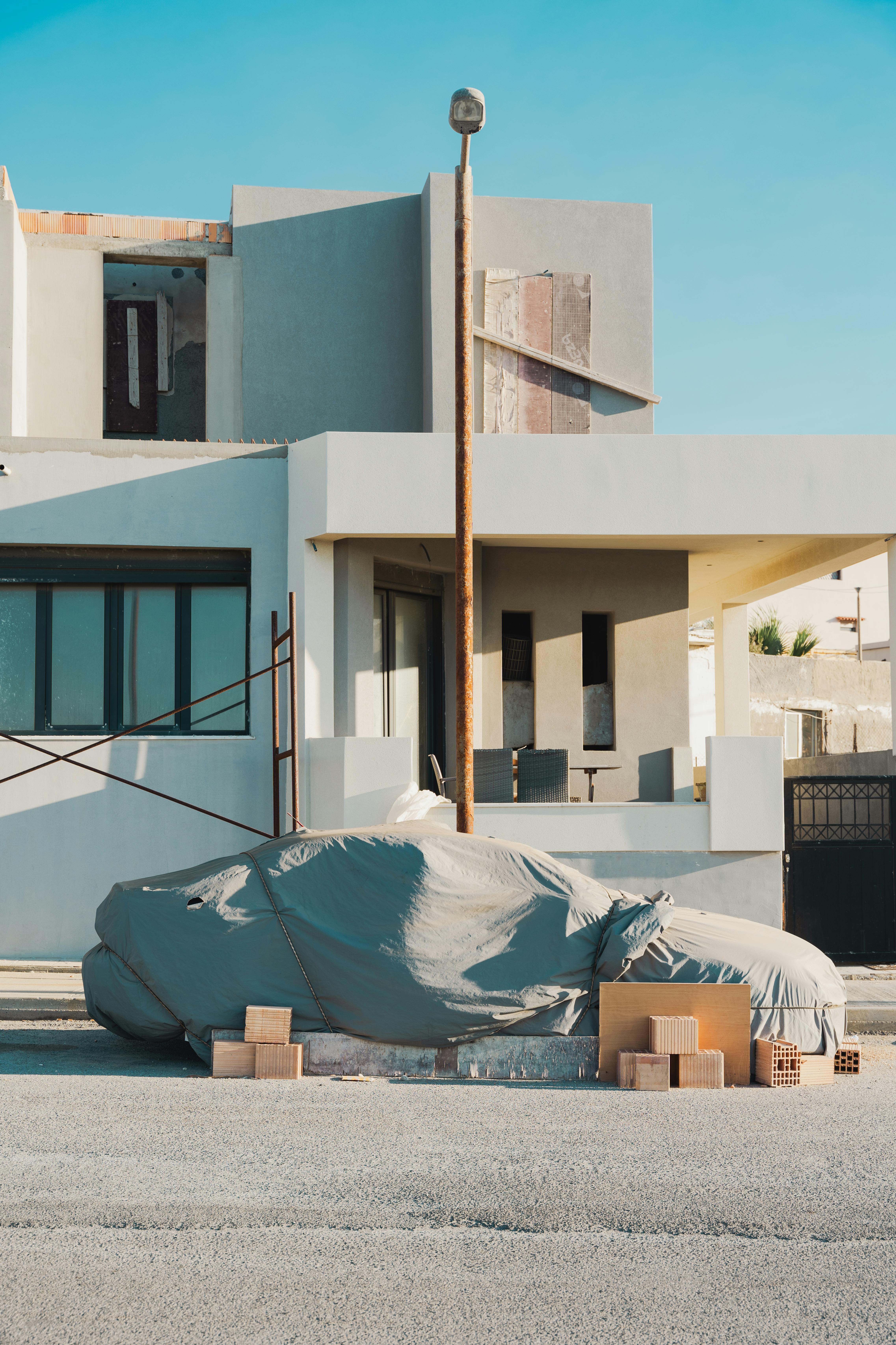 Vehículos embargados Vemos un coche, en una calle, tapado con mantas y cajas de cartón alrededor.