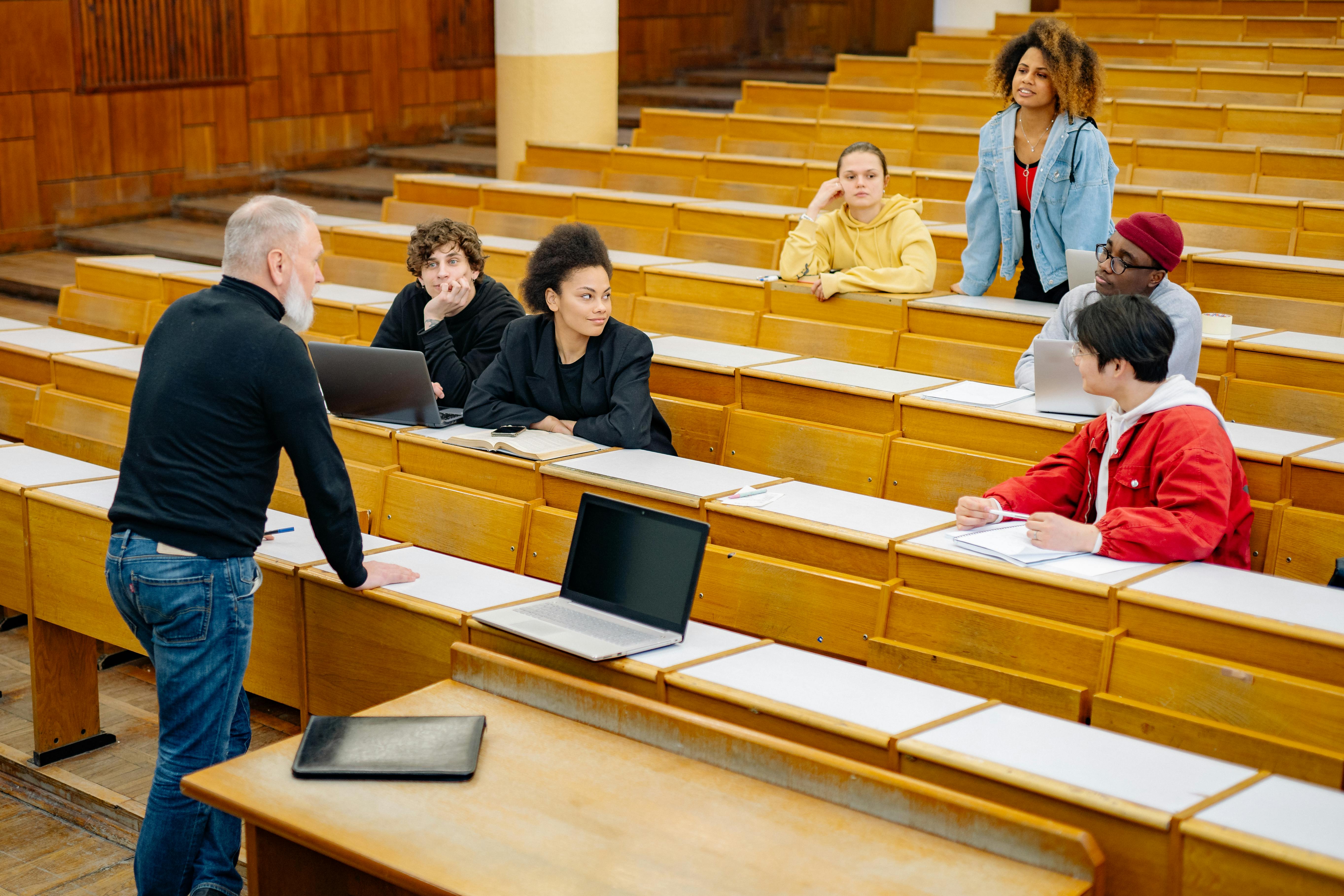 Profesor de Universidad de unos 65 años, haciendo clase a sus alumnos en el aula