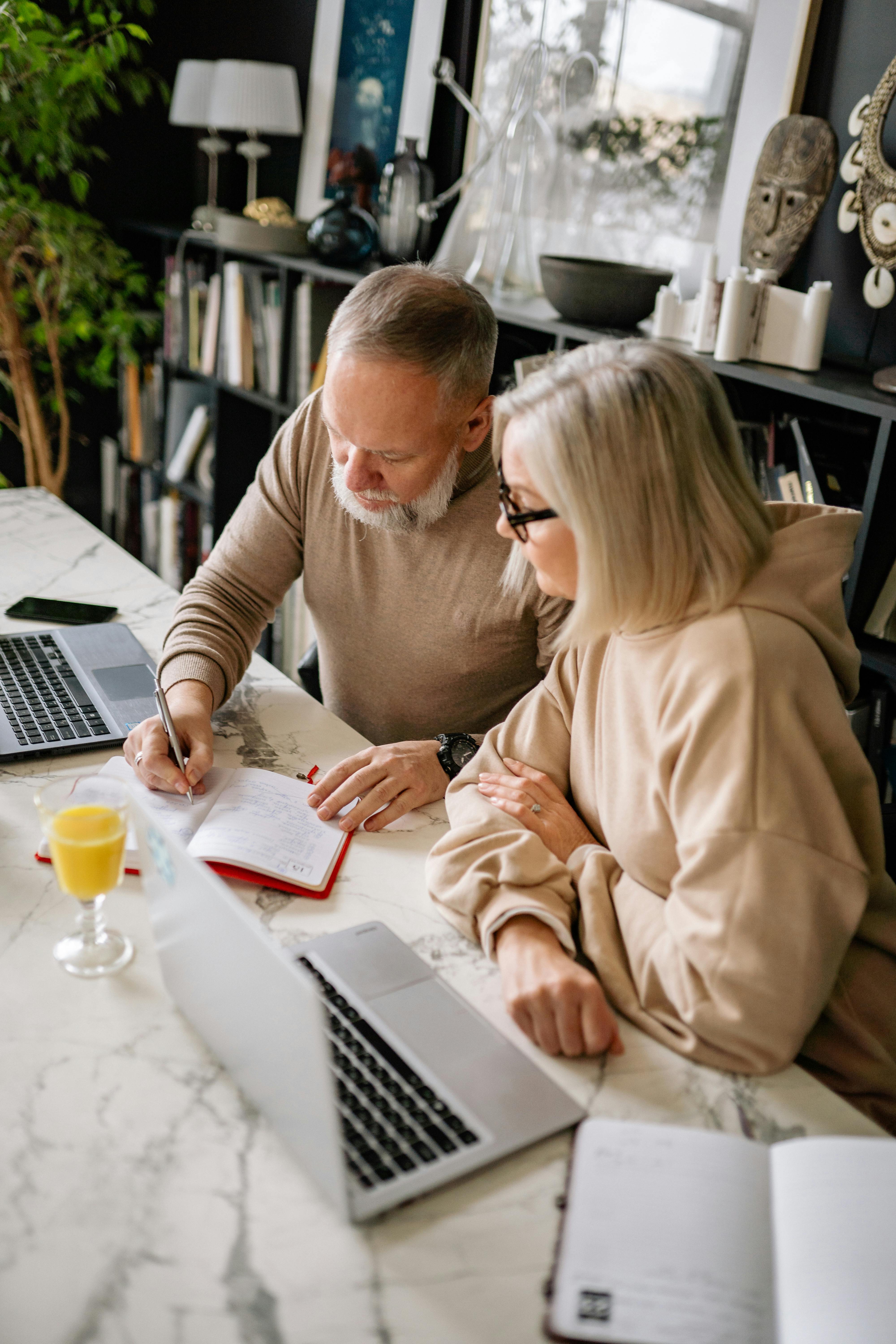Beneficios fiscales en vivienda y patrimonio para mayores de 65 años. Una pareja de jubilados consultando documentos y su ordenador para aplicar las exenciones por venta de vivienda y patrimonio en su Declaración de la Renta.