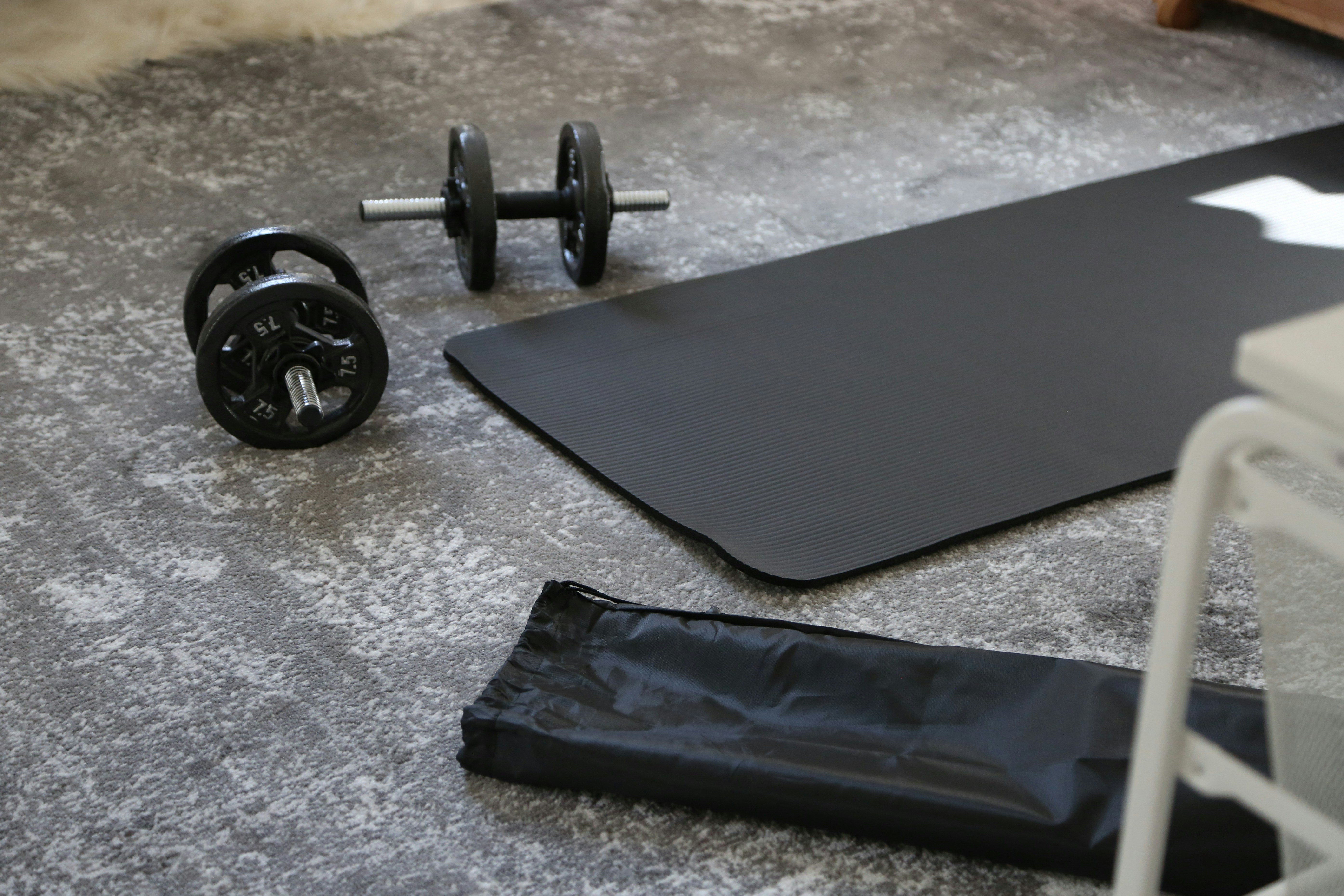El material básico facilita mucho el ponerse en forma sin pagar gimnasio Unas pesas y una esterilla situadas en el suelo de casa
