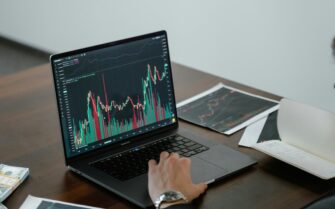 Una mesa con un ordenador y unos gráficos que simulan una inversión.