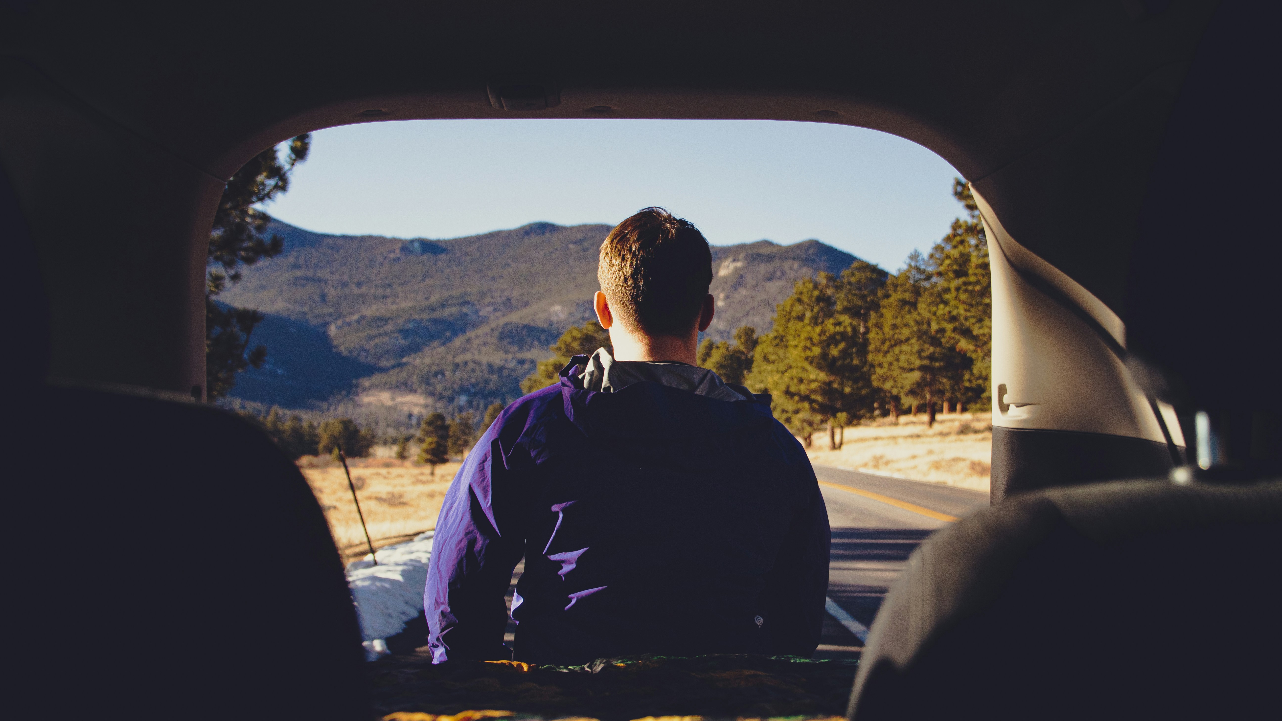 Un joven con su coche frente a un paisaje Un joven mirando al horizonte en un coche de segunda mano
