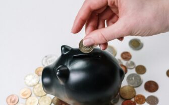 Una mano metiendo monedas en una hucha.