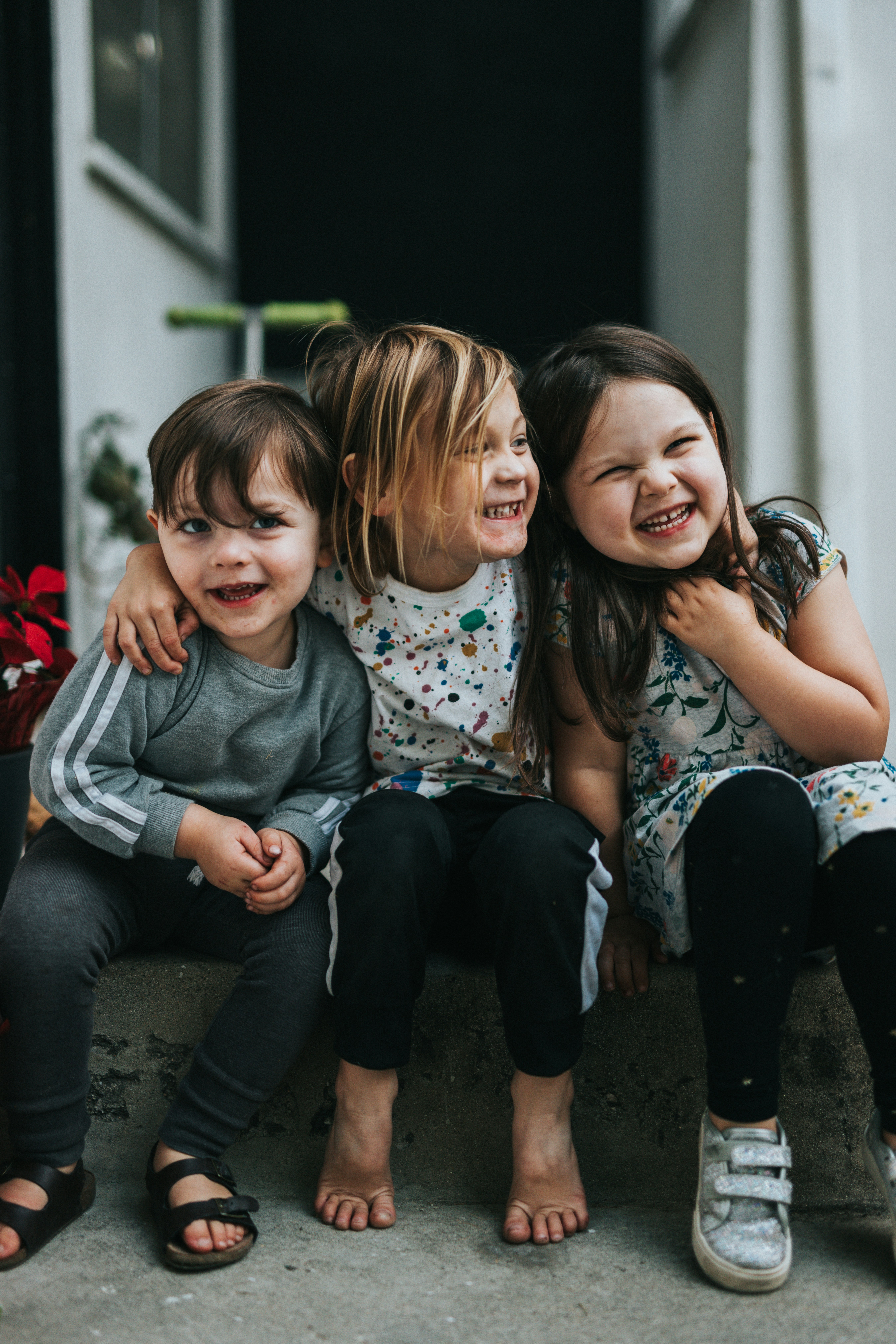 Tres hermanos riéndose en la cocina Tres hermanos sentados en un escalón se abrazan sonrientes