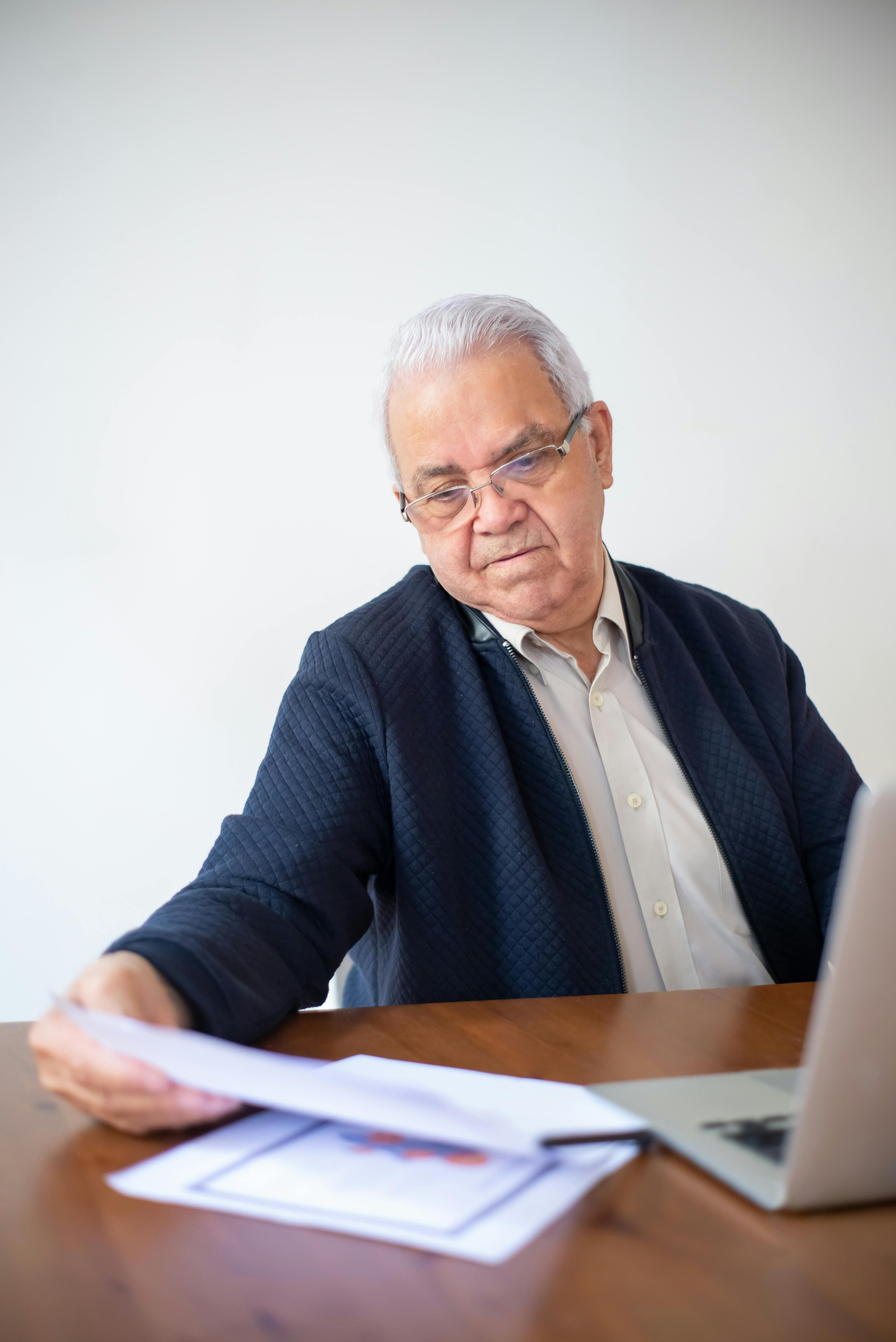 Rentas de capital mobiliario y otras obligaciones fiscales del pensionista Un jubilado revisando gráficos de inversiones y documentos financieros para comprobar si otras rentas, como dividendos o alquileres, le obligan a presentar la Declaración de la Renta