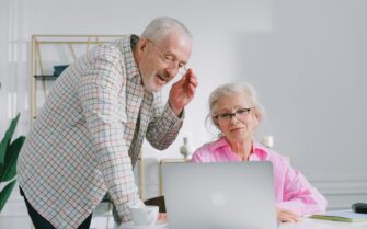 Una mujer y un hombre, de unos 65 años mirando un ordenador portátil