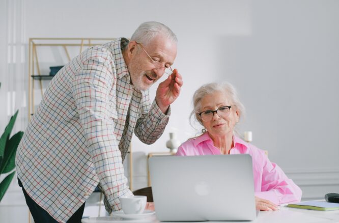 Una mujer y un hombre, de unos 65 años mirando un ordenador portátil