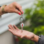 Manos dando y recibiendo una llave de una casa