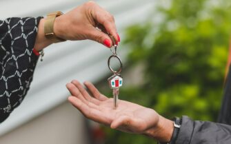 Manos dando y recibiendo una llave de una casa