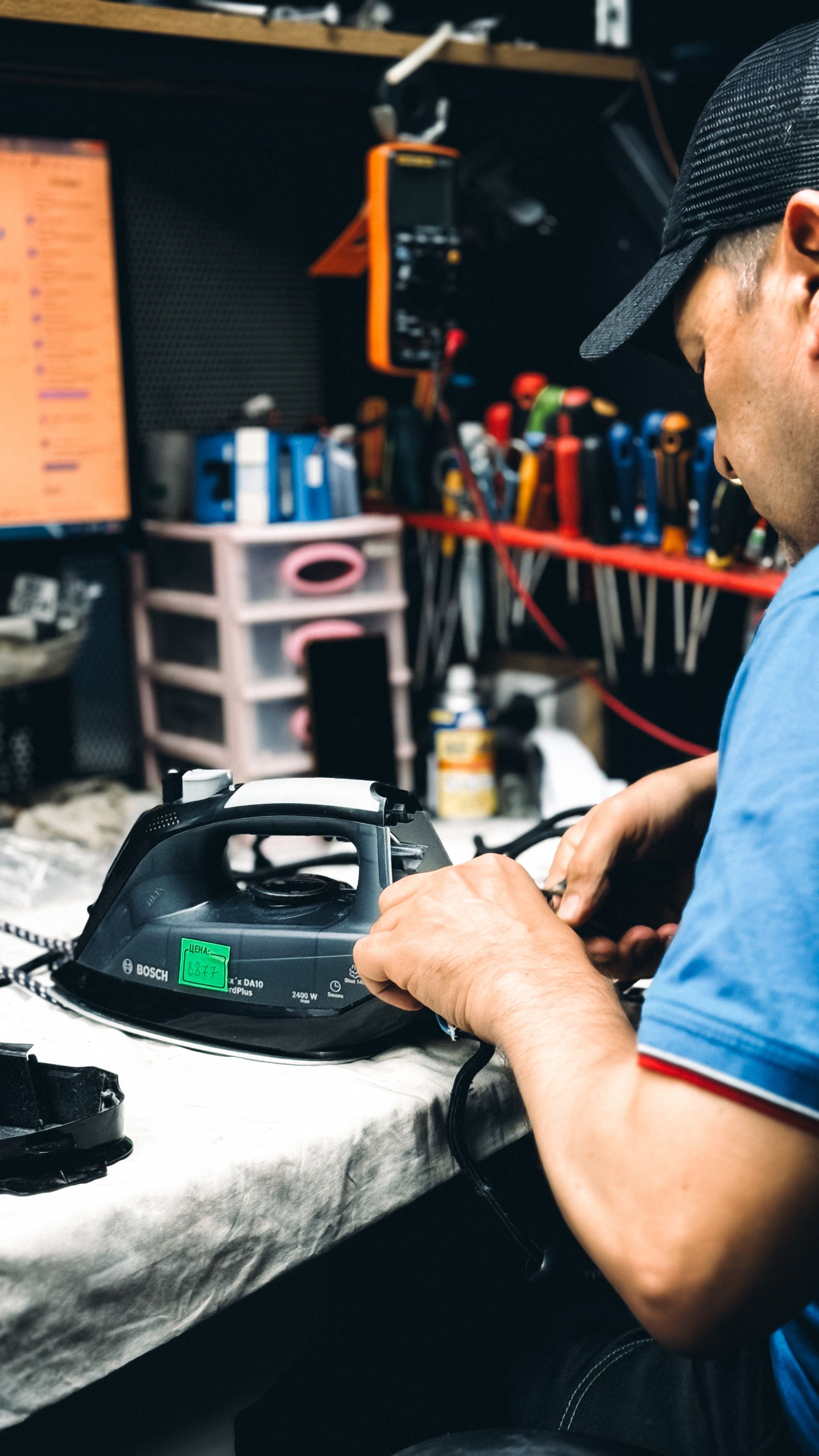 Reparar suele ser una buena opción Técnico en un taller reparando una plancha eléctrica, con herramientas y equipos al fondo.