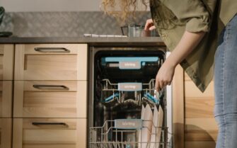 Una mujer carga platos en un lavavajillas automático moderno en un entorno de cocina elegante