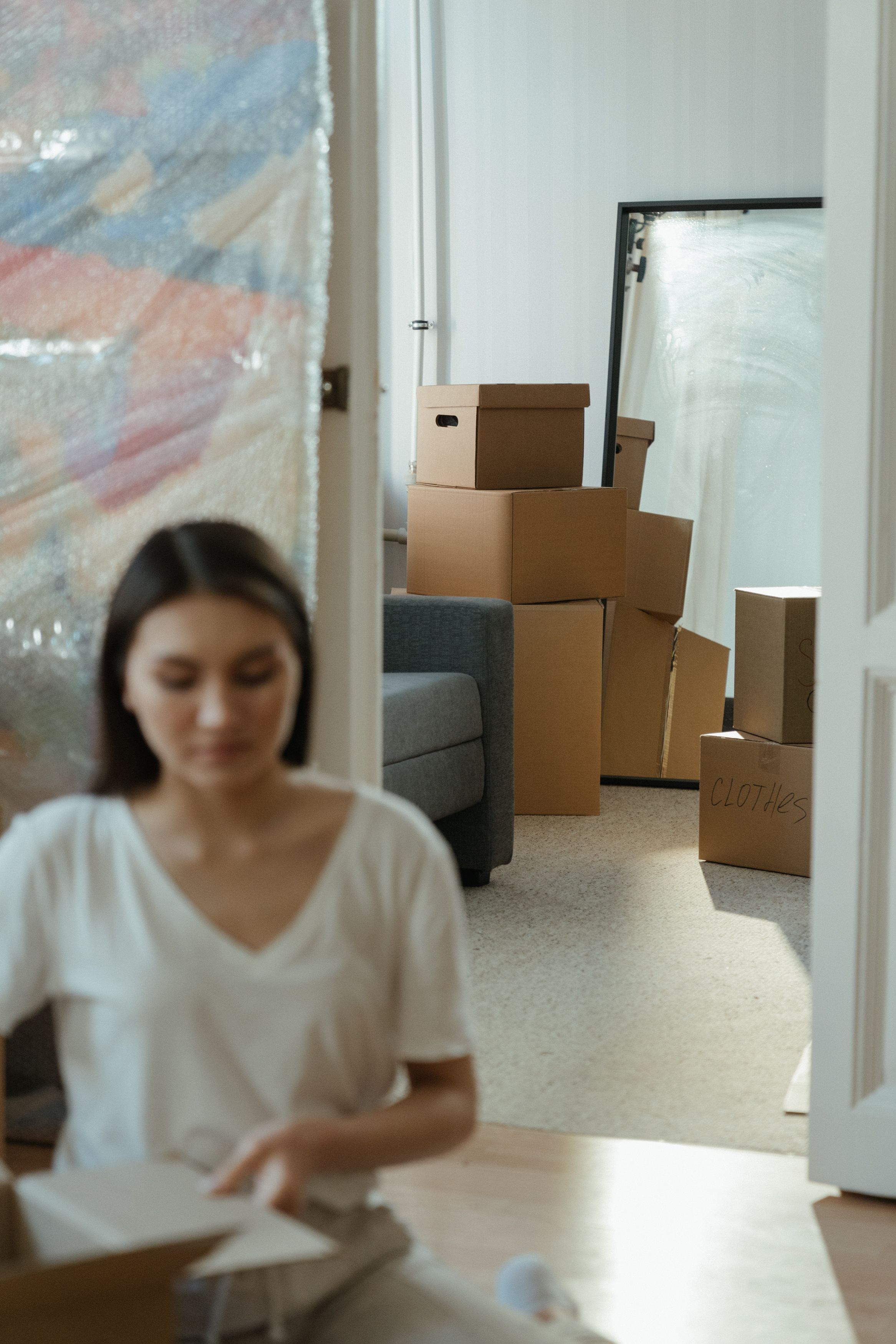 Una economía saneada es clave para afrontar el alquiler o la hipoteca con seguridad Mujer de mediana edad revisa las finanzas con las cajas de una mudanza de fondo