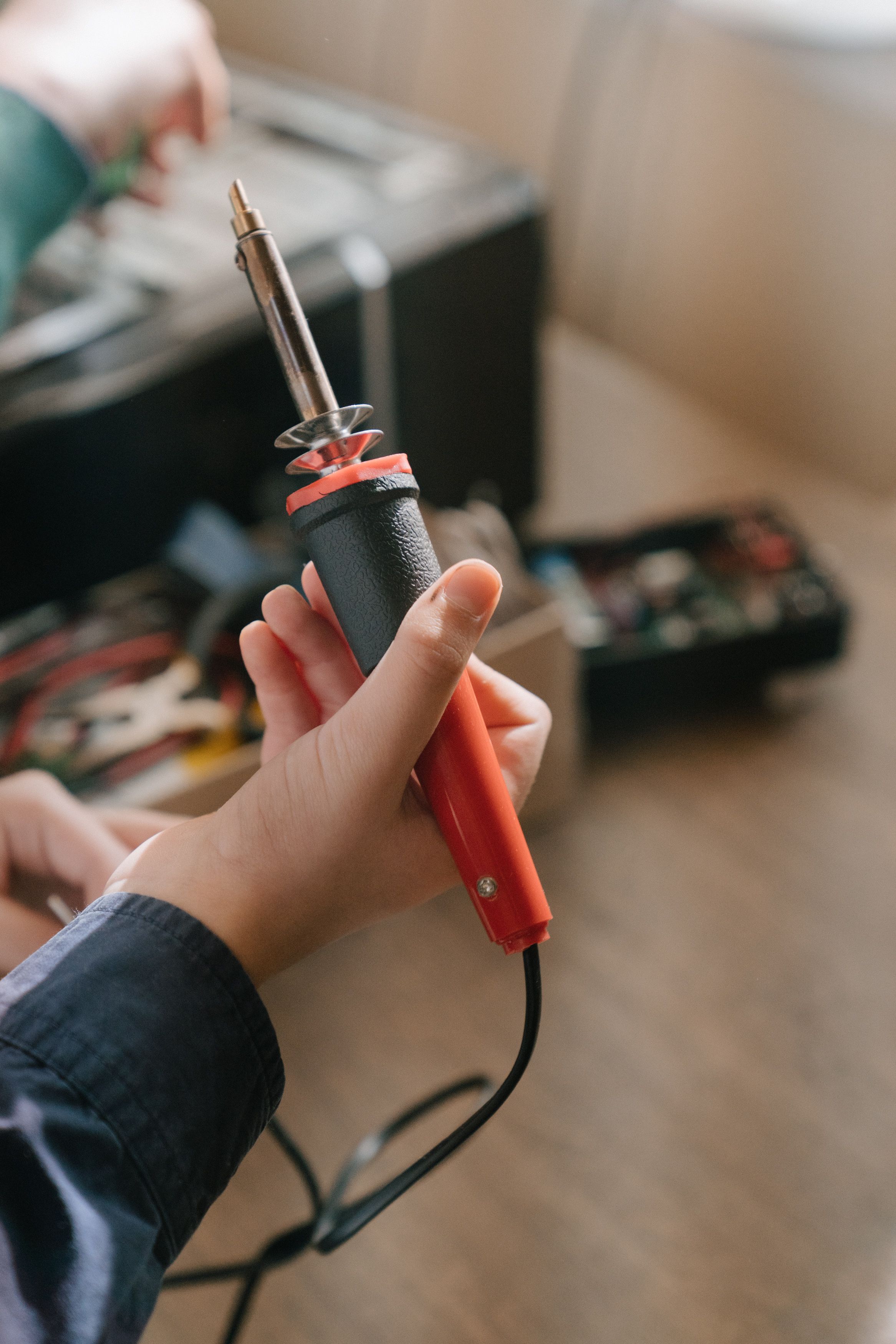Existen alternativas a la compra de aparatos para un uso puntual Mano que sostiene un soldador, lista para realizar una reparación o un montaje electrónico.
