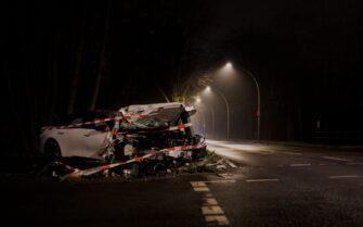 Un coche blanco gravemente dañado tras un accidente de tráfico nocturno y acordonado con cinta de seguridad, ilustrando el escenario de un coche siniestro total.