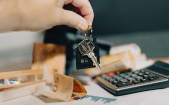 Una mano sostiene las llaves de su vivienda sobre los ahorros para el alquiler