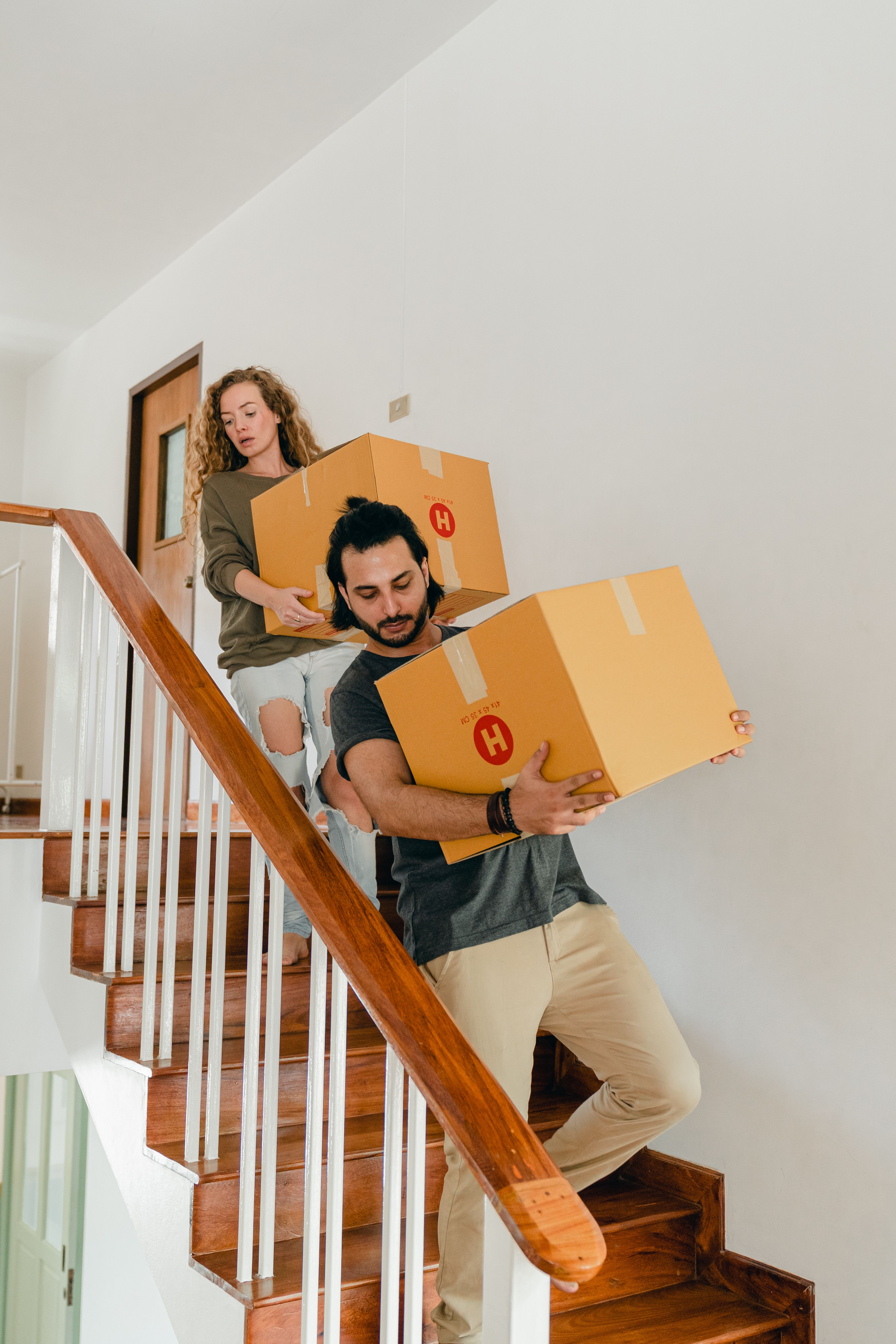 Mudarse a una vivienda más pequeña o a las afueras es una de las soluciones más utilizadas por las parejas jóvenes Una pareja baja las escaleras cargada con cajas de mudanza