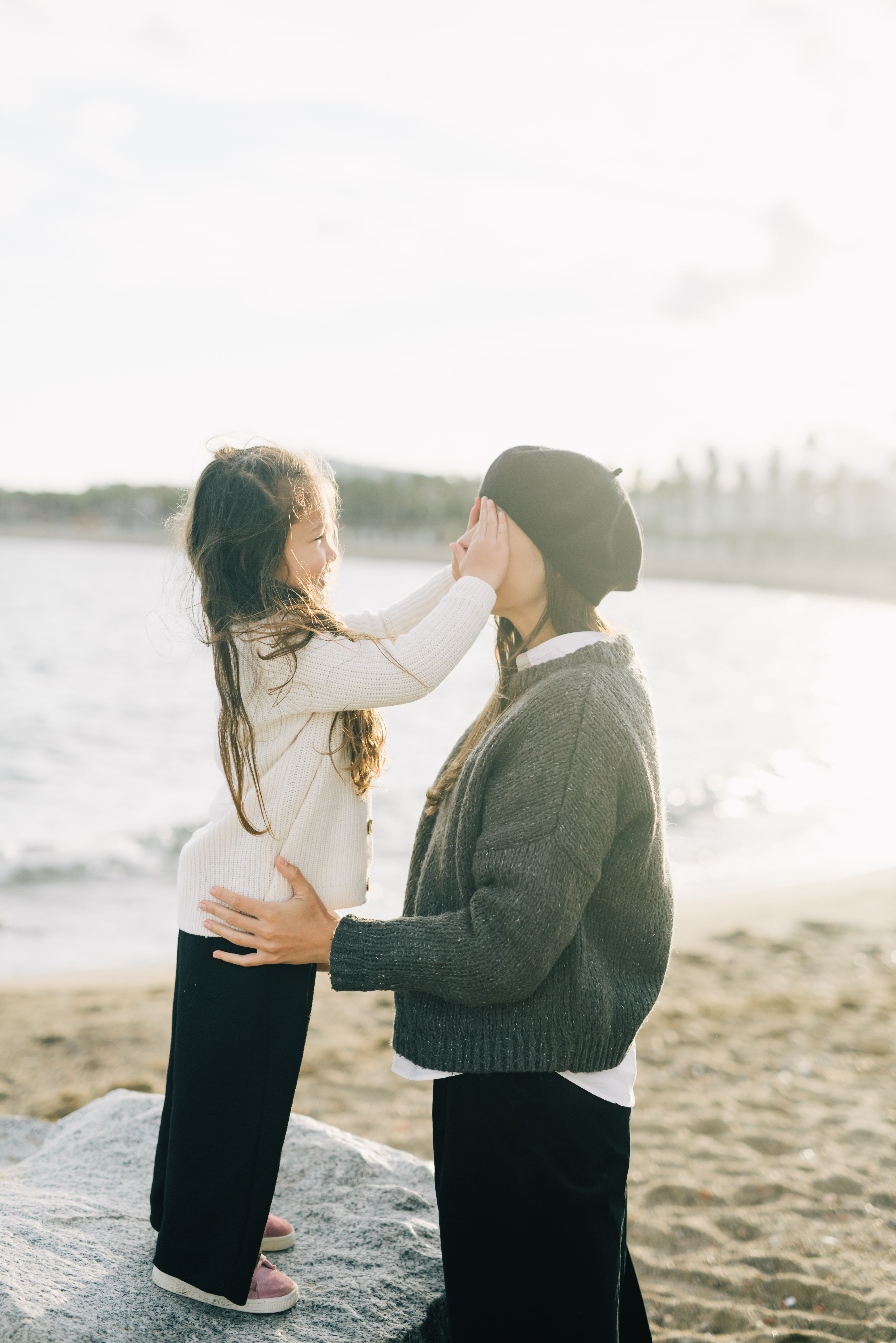 Un momento monoparental lleno de felicidad Una madre recibe una caricia de su hija en la frente mientras están en la playa