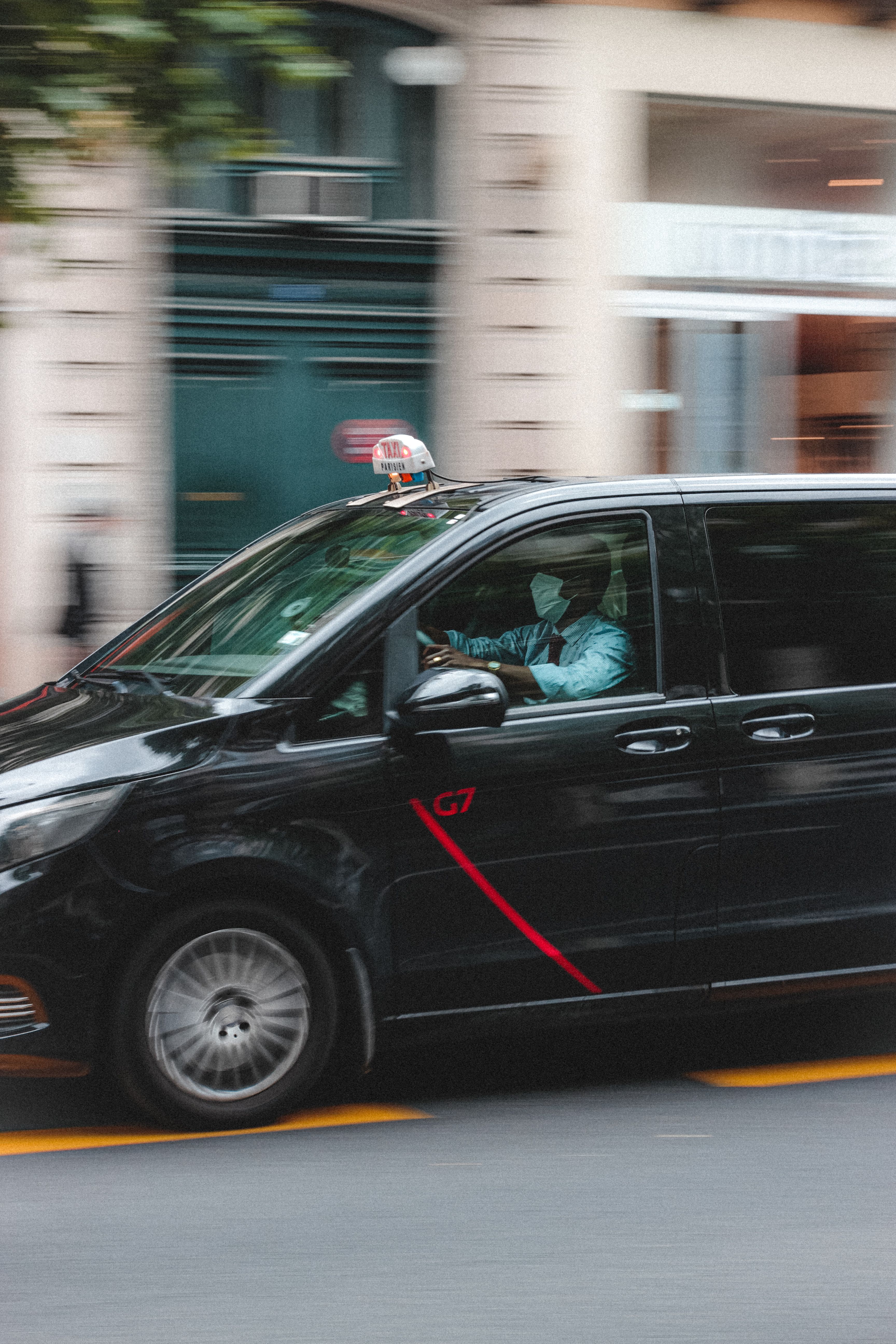 Comparativa entre el servicio de taxi urbano y las licencias VTC Un taxi negro en movimiento circulando por una calle urbana, ilustrando las diferencias de operativa y contratación frente a un vehículo VTC.